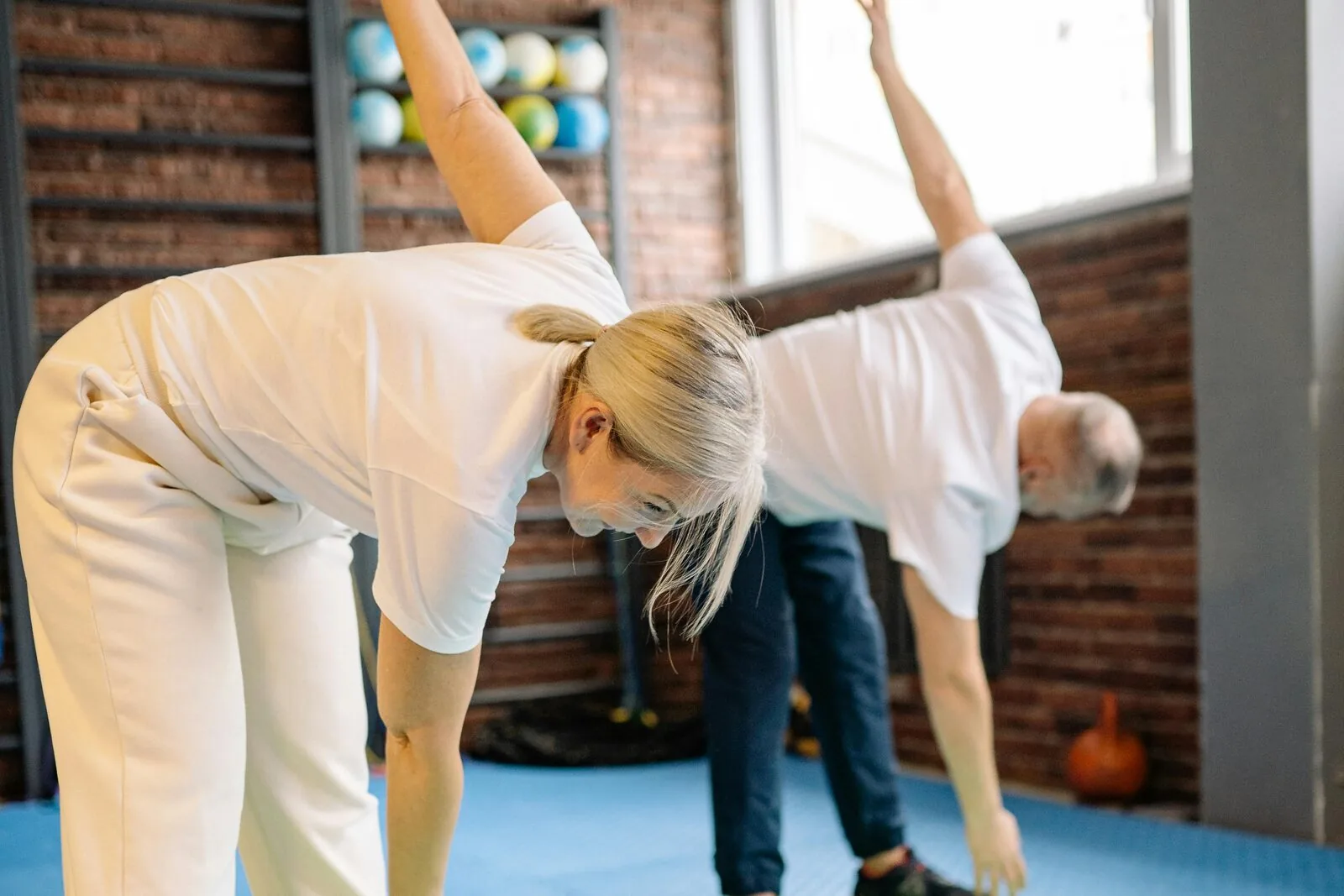 Two participants performing standing side stretches in a Cancer Rehab exercise class at Eramosa Physiotherapy Associates